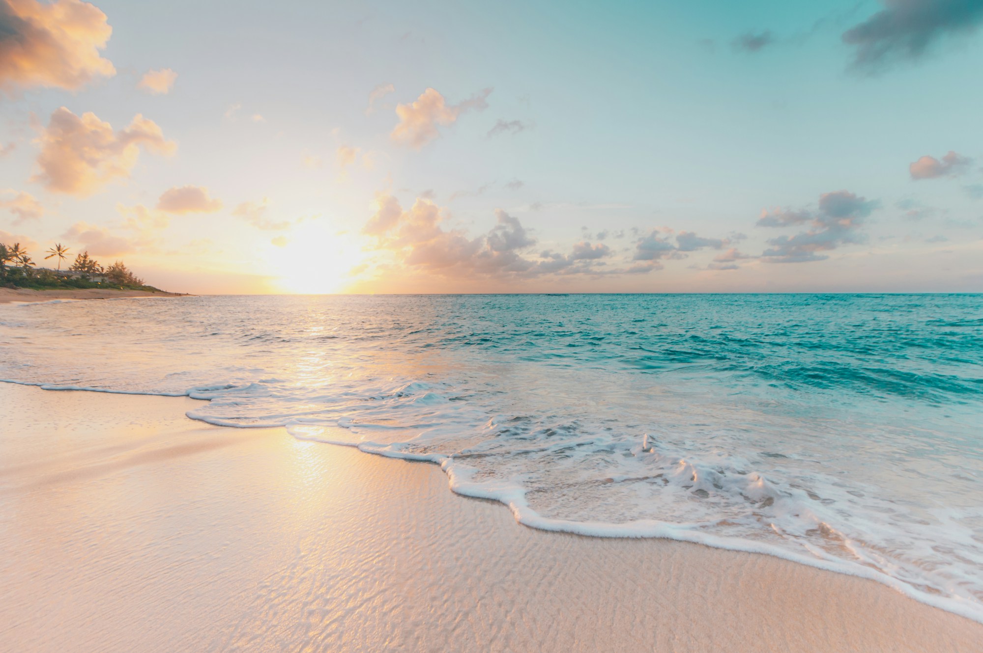 Golven op een licht strand bij zonsondergang
